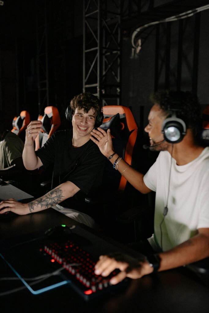 Group of young male gamers in gaming chairs enjoying an esports tournament indoors, wearing headphones and smiling.